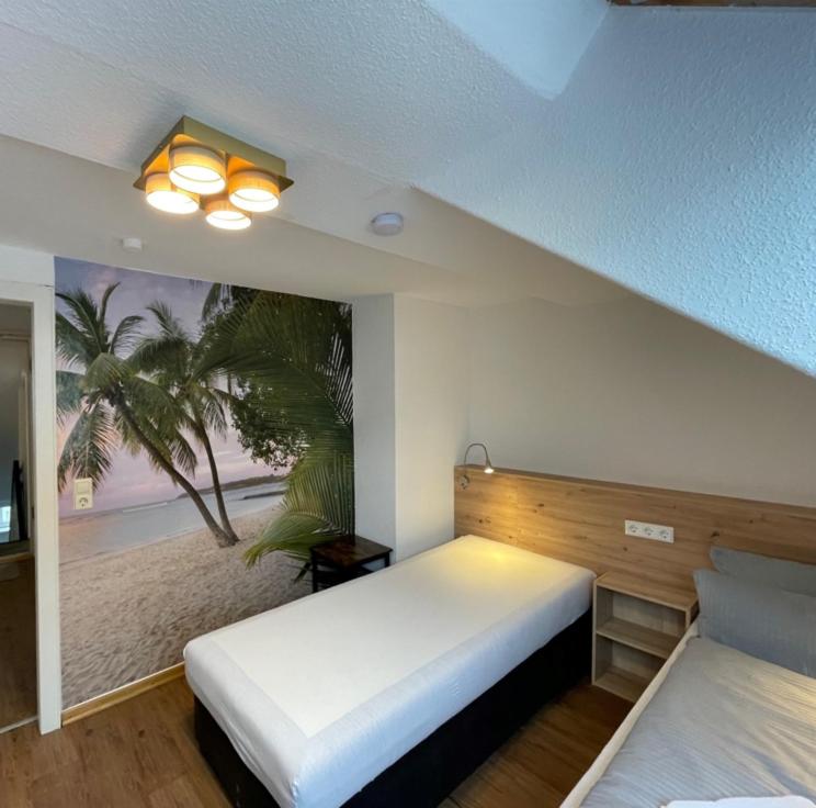 una camera da letto con due letti e un dipinto di una palma di GrünRaum Deister ad Hannover