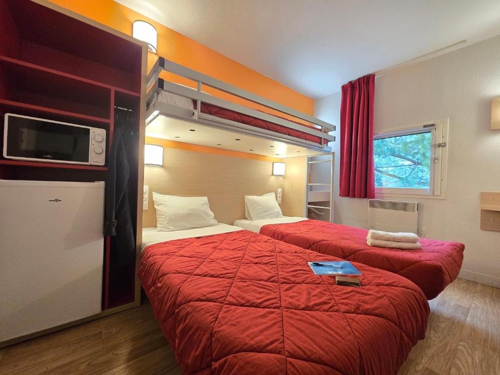 a hotel room with two beds with red sheets at Premiere Classe Valence - Bourg Les Valence in Bourg-lès-Valence