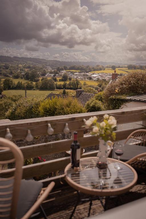 a table with a bottle of wine and flowers on a balcony at Central Llandeilo with Stunning views- Sleeps 2 in Llandeilo