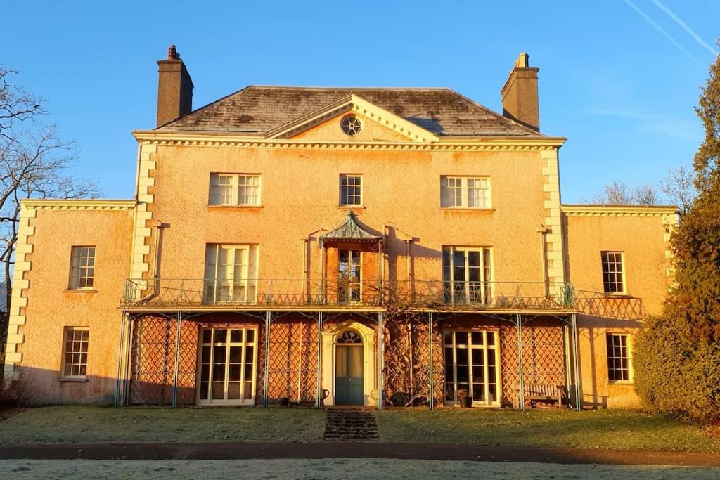a large yellow brick building with a balcony at Little Plas in Crickhowell