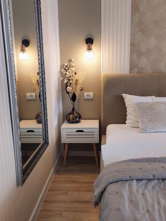 a bedroom with a bed and a mirror and a vase with flowers at ALDIRA Studio Arena Nationala in Bucharest