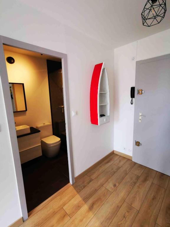 a bathroom with a toilet and a red object on the wall at T1 bis à deux pas du Belvédère in Thonon-les-Bains