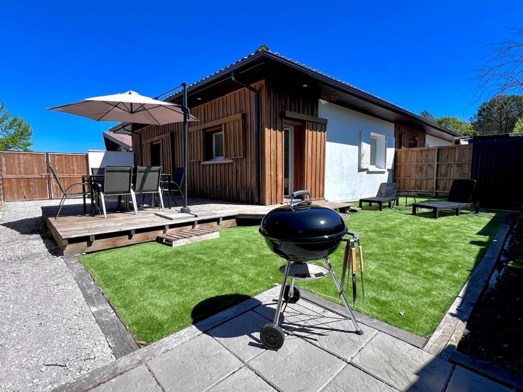 - un barbecue dans une cour à côté d'une maison dans l'établissement Le Baleste - Duplex Cosy, à Mimizan