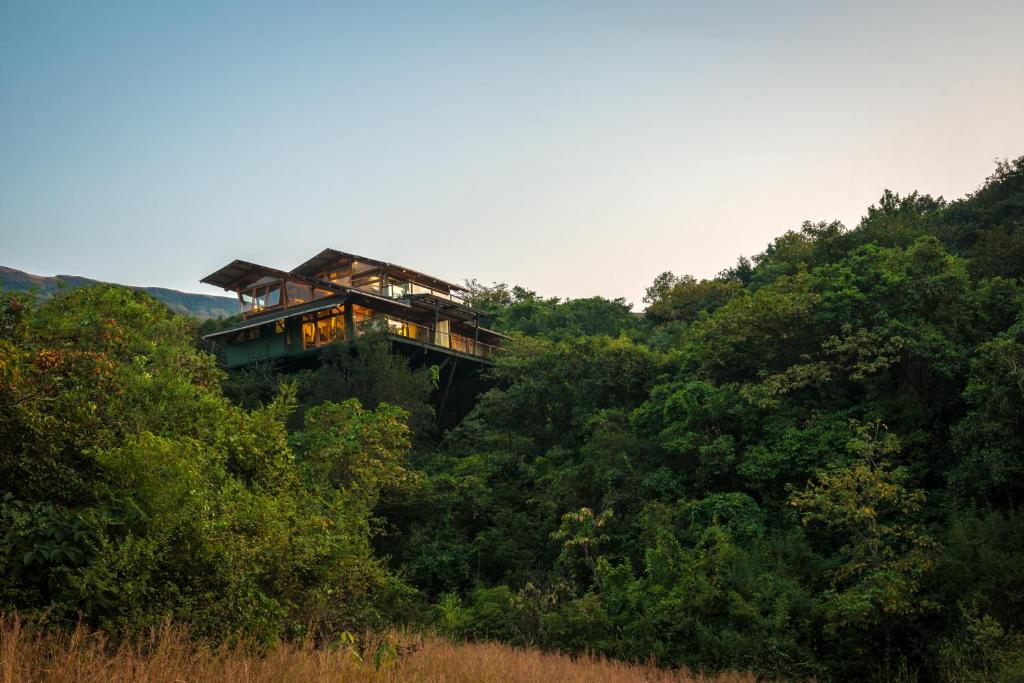 uma casa no topo de uma colina na floresta em The Machan em Lonavala