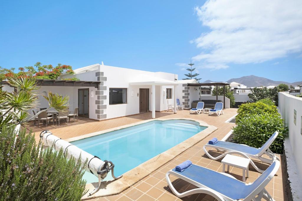 a villa with a swimming pool and patio furniture at Casa Calma in Playa Blanca