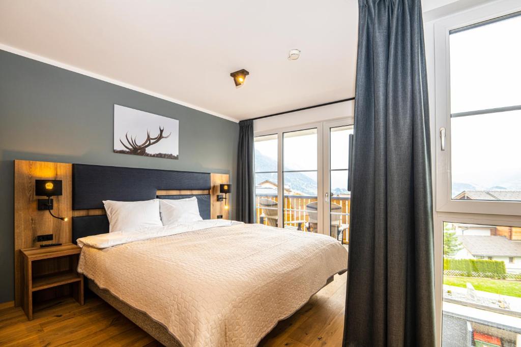 a bedroom with a bed and a large window at AlpenParks Hotel & Apartment Alpendorf in Sankt Johann im Pongau