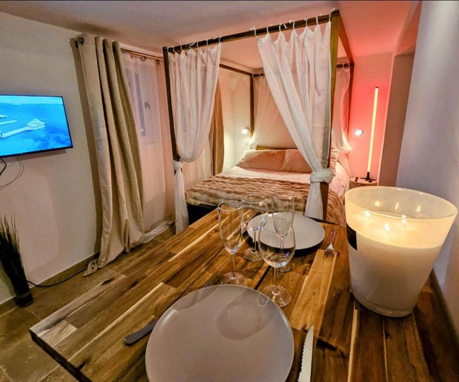 - une chambre avec un lit et 2 tables avec des verres à vin dans l'établissement Love Room Provençale studio, au Castellet