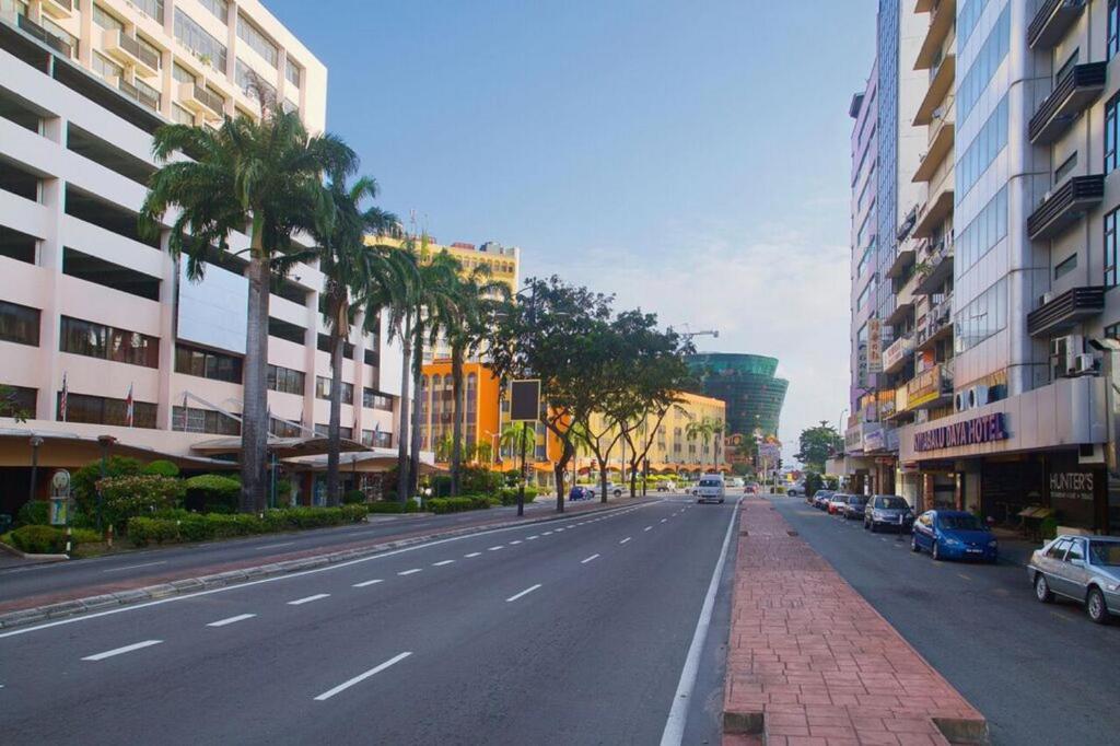 uma rua urbana vazia com palmeiras e edifícios em Kinabalu Daya Hotel em Kota Kinabalu