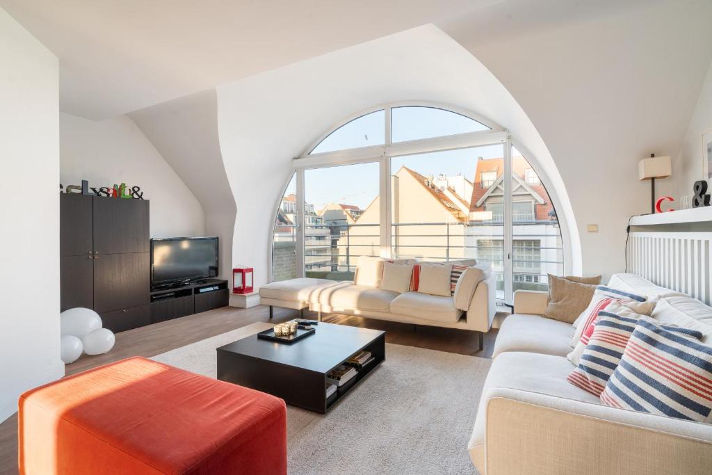 a living room with a couch and a table at Stijlvol & lichtrijk Penthouse app met parking in Knokke-Heist