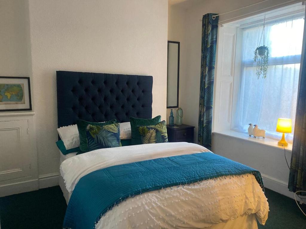 a bedroom with a bed with a blue headboard and a window at Cosy Flat in Y Felinheli in Y Felinheli