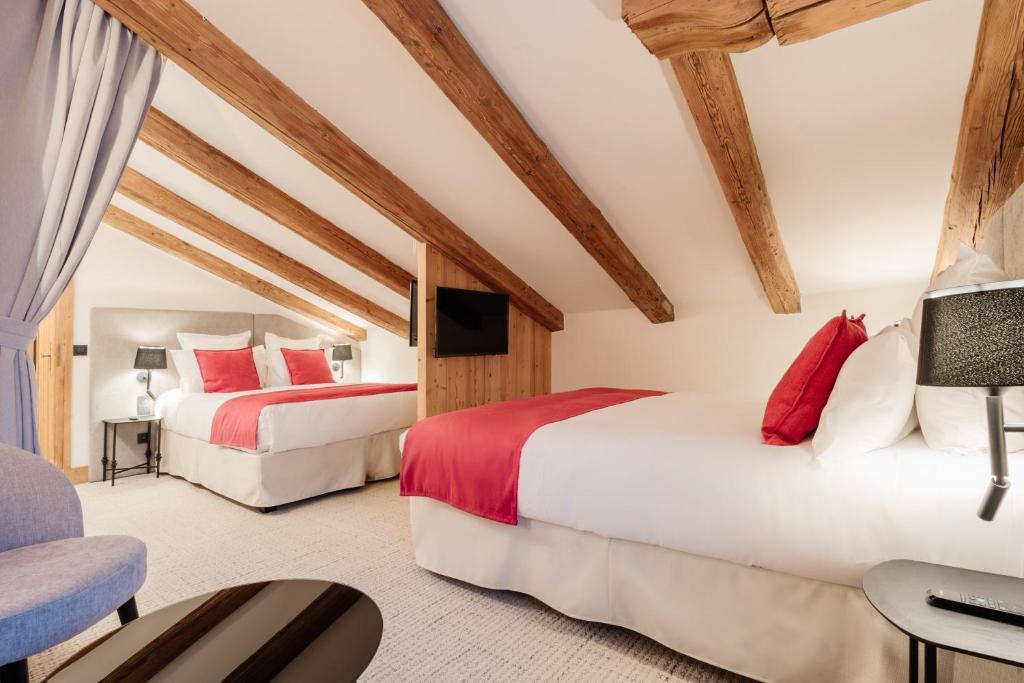 two beds in a room with wooden ceilings at La Ferme du Golf in Megève