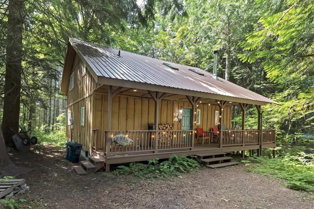 a wooden cabin in the woods with a deck at Twin Maples | WiFi, River Access, BBQ in Packwood