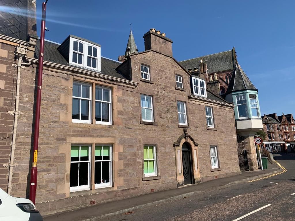 an old brick building on the corner of a street at Squirrel Away Apartments in Crieff