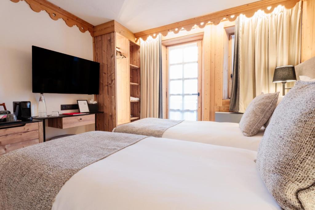a bedroom with two beds and a flat screen tv at La Ferme du Golf in Megève