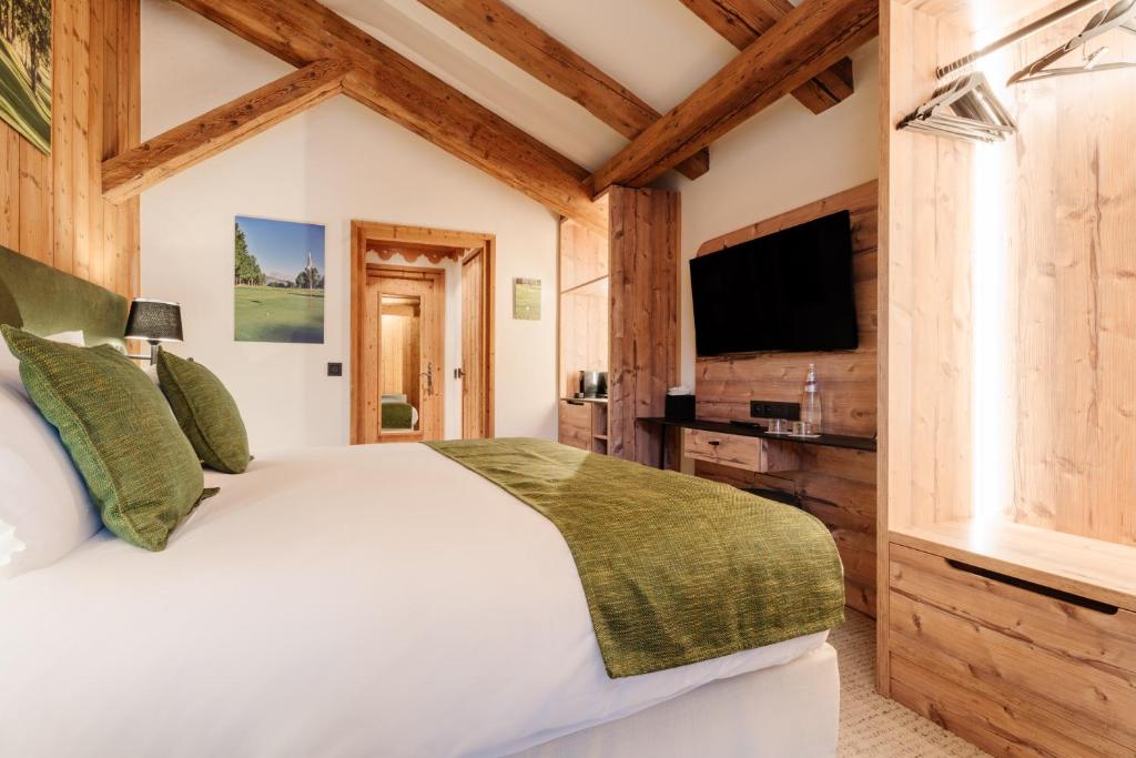 a bedroom with a white bed and a flat screen tv at La Ferme du Golf in Megève