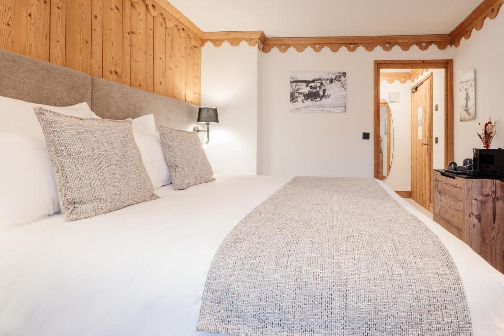 a bedroom with a large white bed with pillows at La Ferme du Golf in Megève