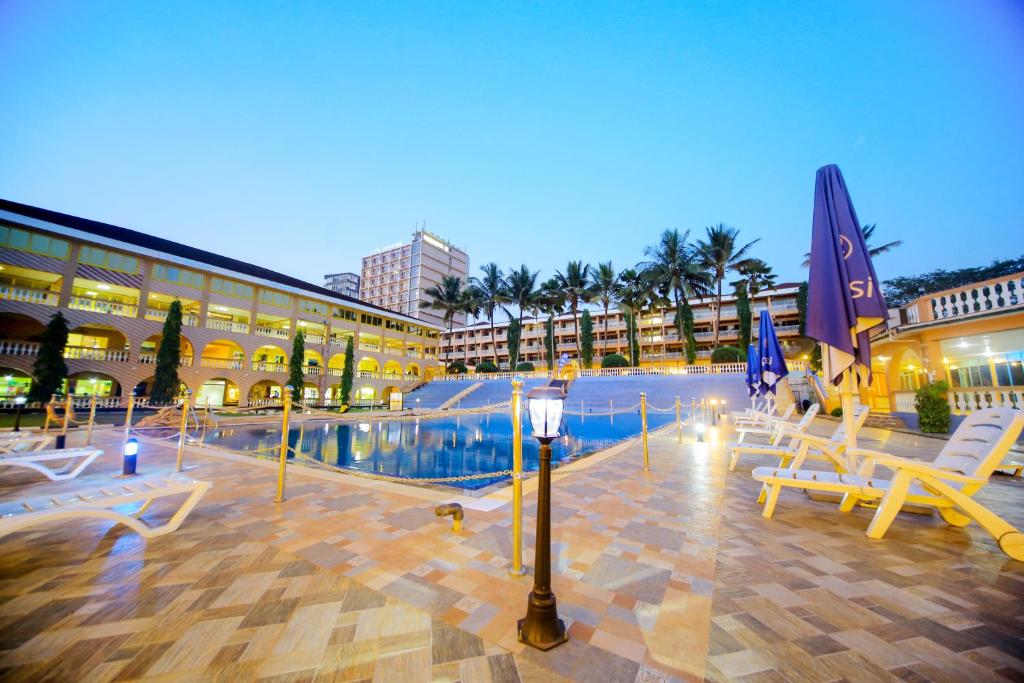 a resort with a pool and chairs and a building at Hotel Africana in Kampala