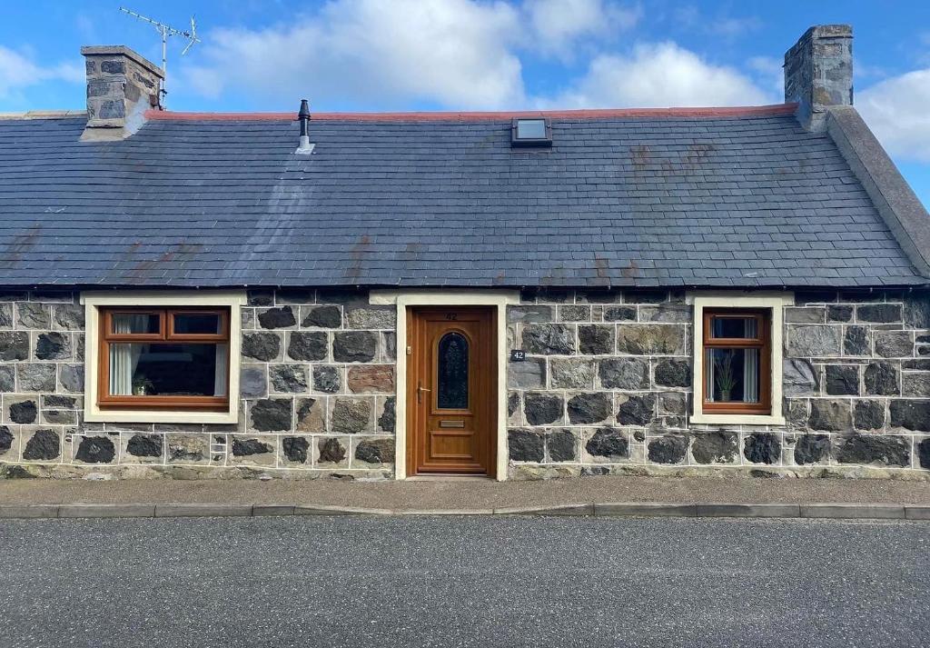 a stone building with a brown door and windows at Number Forty Two, Portsoy - A 3 bedroom cottage with sea views in Portsoy