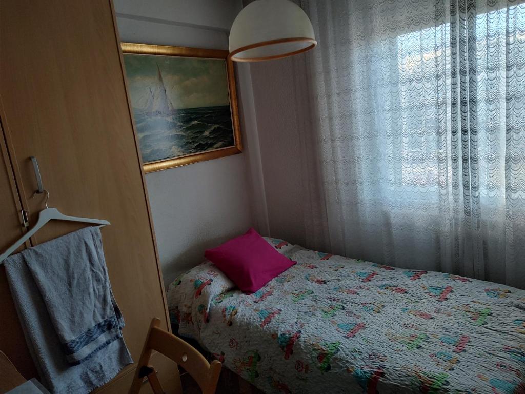 Dormitorio pequeño con cama con almohada rosa en Habitación Privada Alameda de Osuna, en Madrid