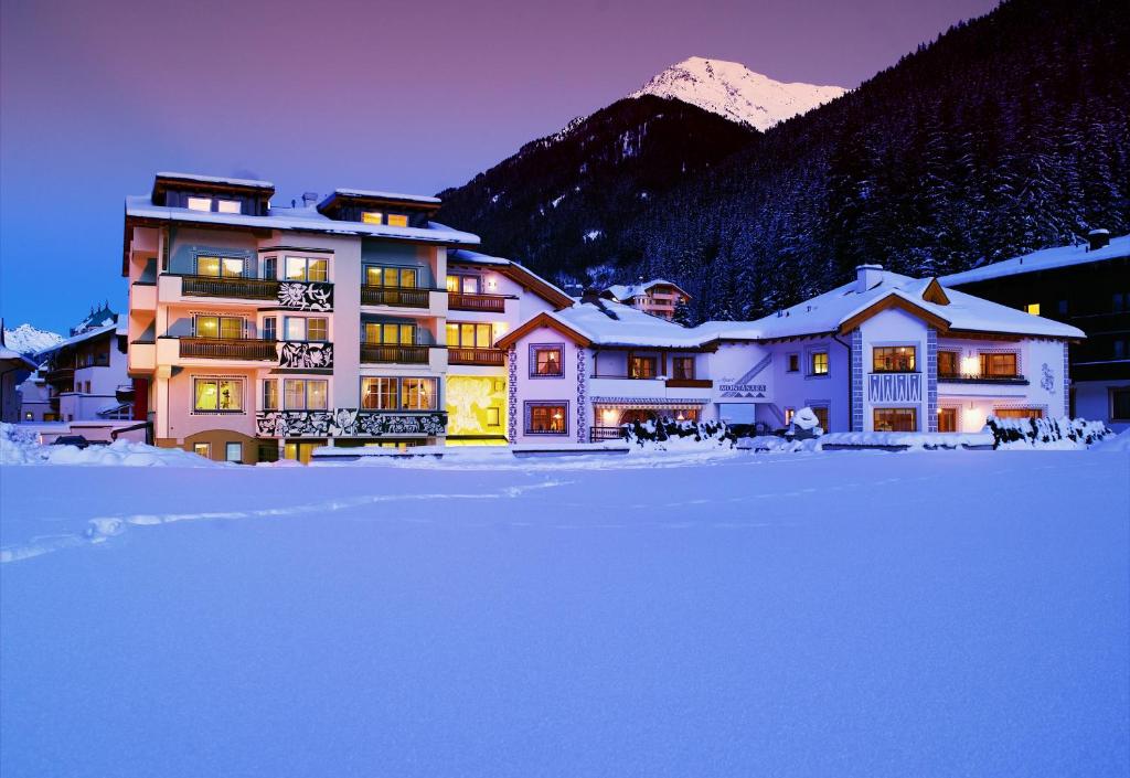 a large building in the snow in front of a mountain at Apart Montanara in Ischgl