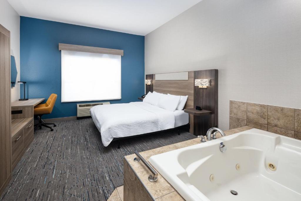a hotel room with a bed and a tub at Holiday Inn Express & Suites - Green Bay East by IHG in Green Bay