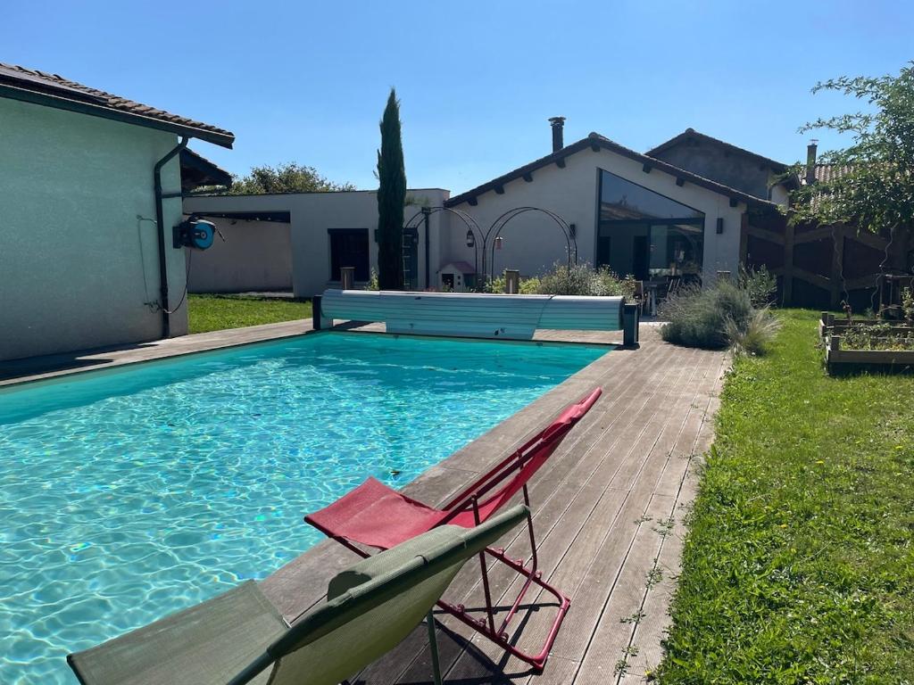une piscine avec deux chaises et une maison dans l'établissement La Fontaine, Maison avec Piscine à 8 mn de Belleville, à Taponas