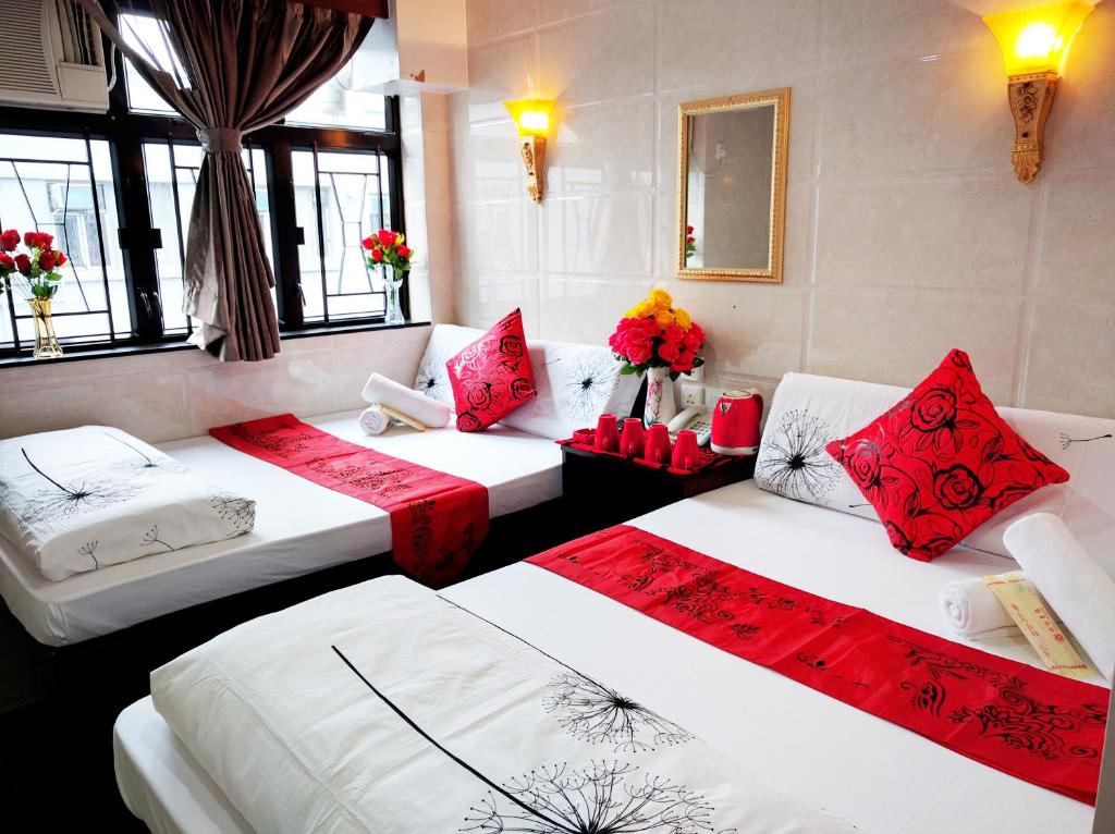 a room with three beds with red and white pillows at Day and Night Hostel Block D 10th floor in Hong Kong