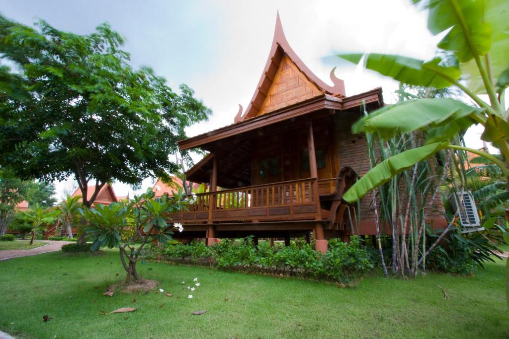 uma casa de madeira com um deque na relva em Ayodhara Village em Phra Nakhon Si Ayutthaya