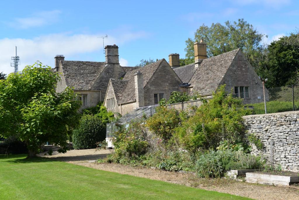 an old stone house with a stone wall at 5 star Cotswold luxury with orchard garden in Cirencester