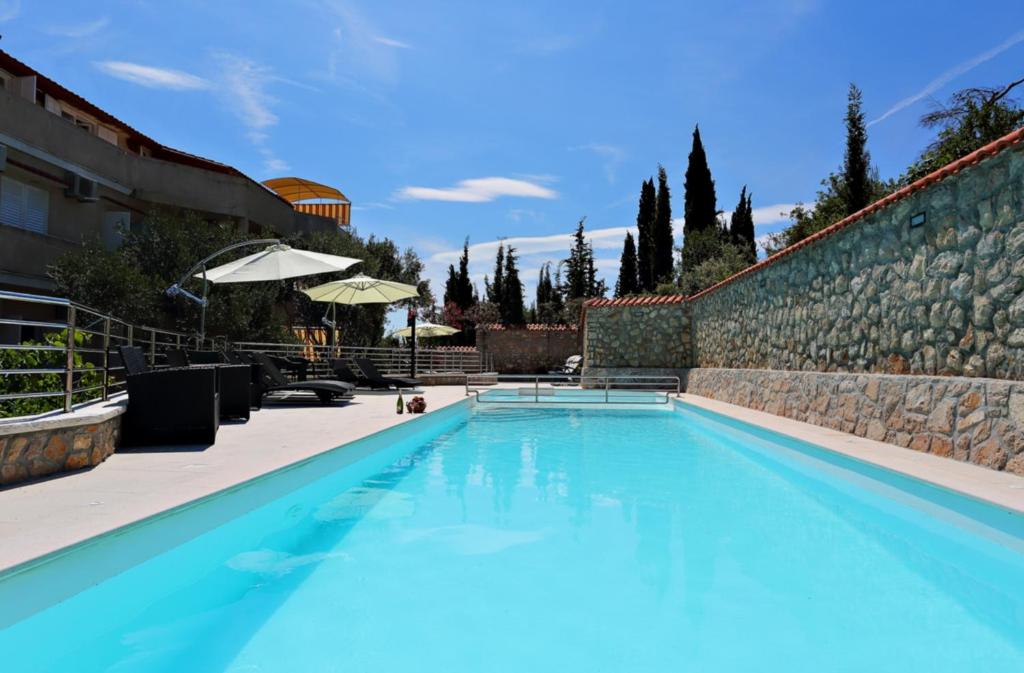 a large blue swimming pool next to a stone wall at Villa Dinastija in Kali