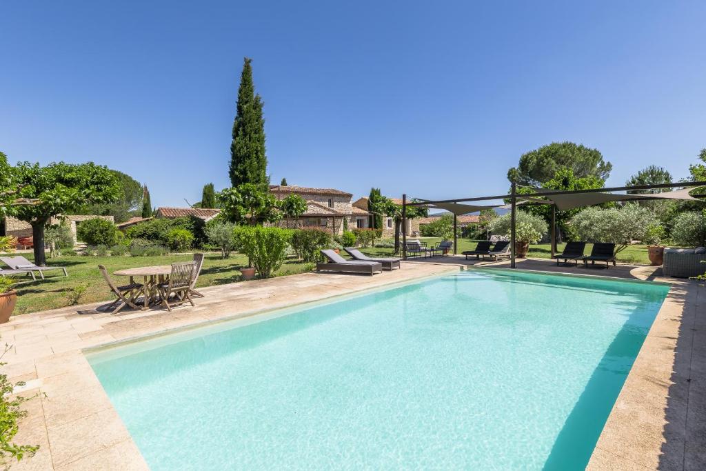 a swimming pool in a yard with a table and chairs at Mas Oréa côté piscine in Gordes