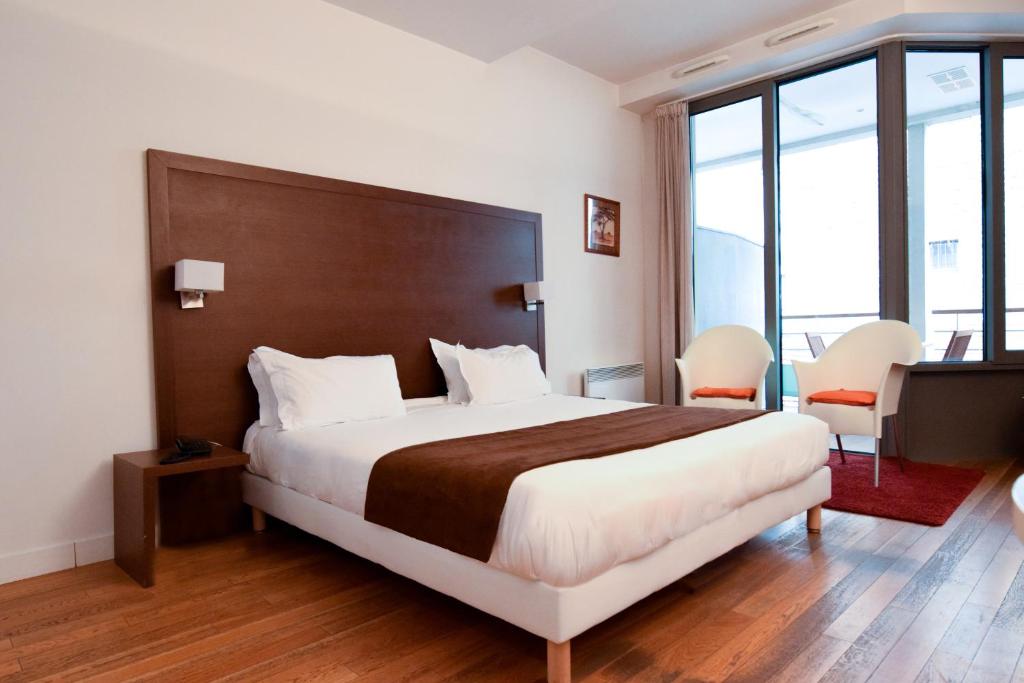Cette chambre d'hôtel dispose d'un grand lit et de fenêtres. dans l'établissement Residhotel Imperial Rennequin, à Paris