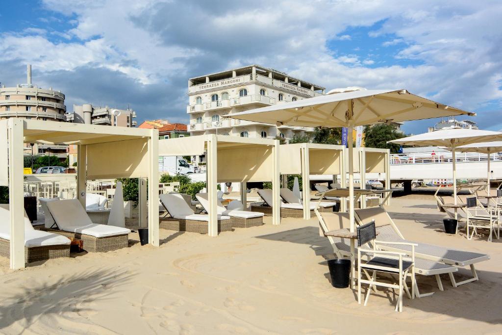 un patio con tavoli, sedie e ombrelloni di Terrazza Marconi Hotel&Spamarine a Senigallia