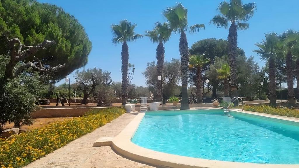 einen Pool in einem Park mit Palmen in der Unterkunft Macchia Salentina in Baia Di Gallipoli