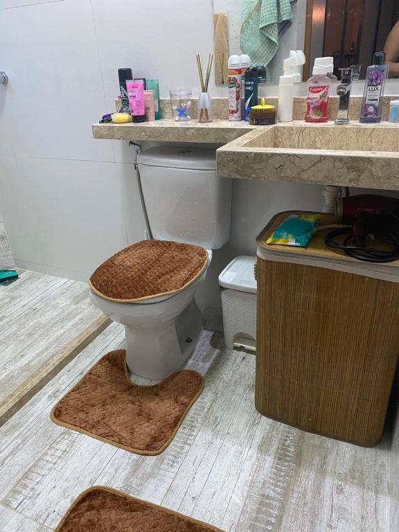 a bathroom with a toilet and a sink with rugs at Centro próximo à rua das pedras in Búzios