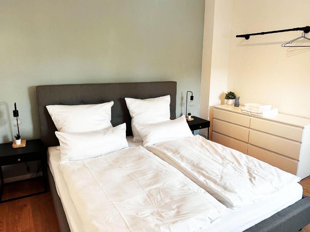 une chambre avec un grand lit avec des draps et des oreillers blancs dans l'établissement 60qm Apartment mit 2 Betten in Viersen - Central - High ceiling, à Viersen