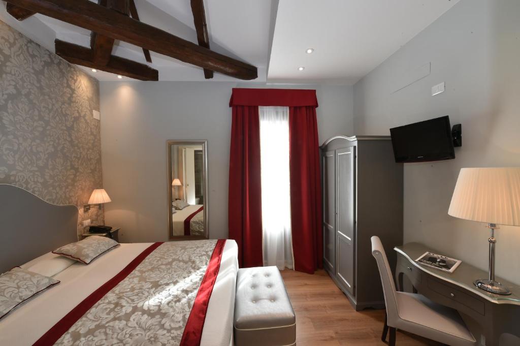 a bedroom with a bed and a desk and a window at Hotel Villa Rosa in Venice