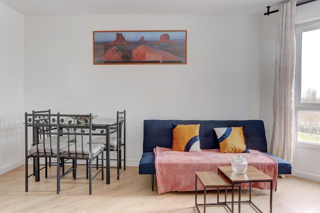 ein Wohnzimmer mit einem blauen Sofa und Stühlen in der Unterkunft Le Sully - Mantes la jolie in Mantes-la-Jolie