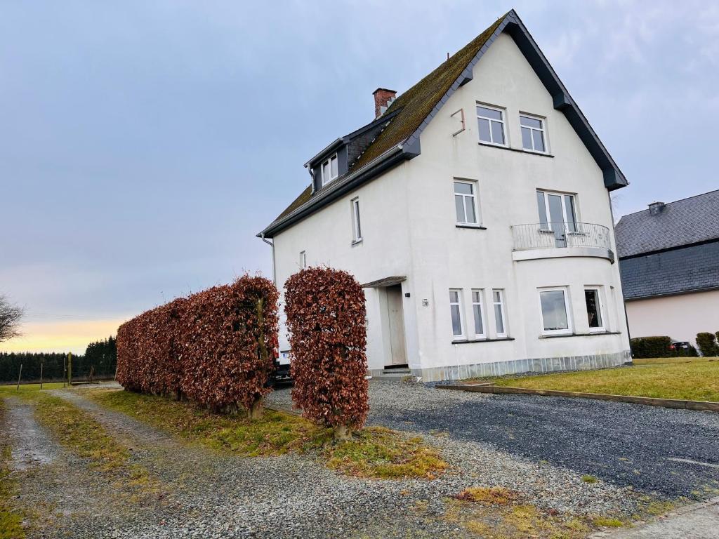 una gran casa blanca con arbustos rojos delante de ella en Ferienhaus Zum Brand, en Bütgenbach