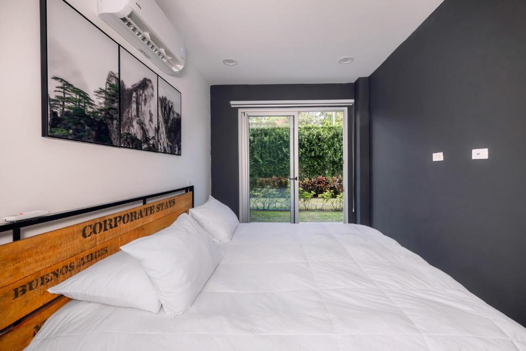 ein Schlafzimmer mit einem großen weißen Bett und einem Fenster in der Unterkunft Urban Flats Studios by Corporate Stays in San José