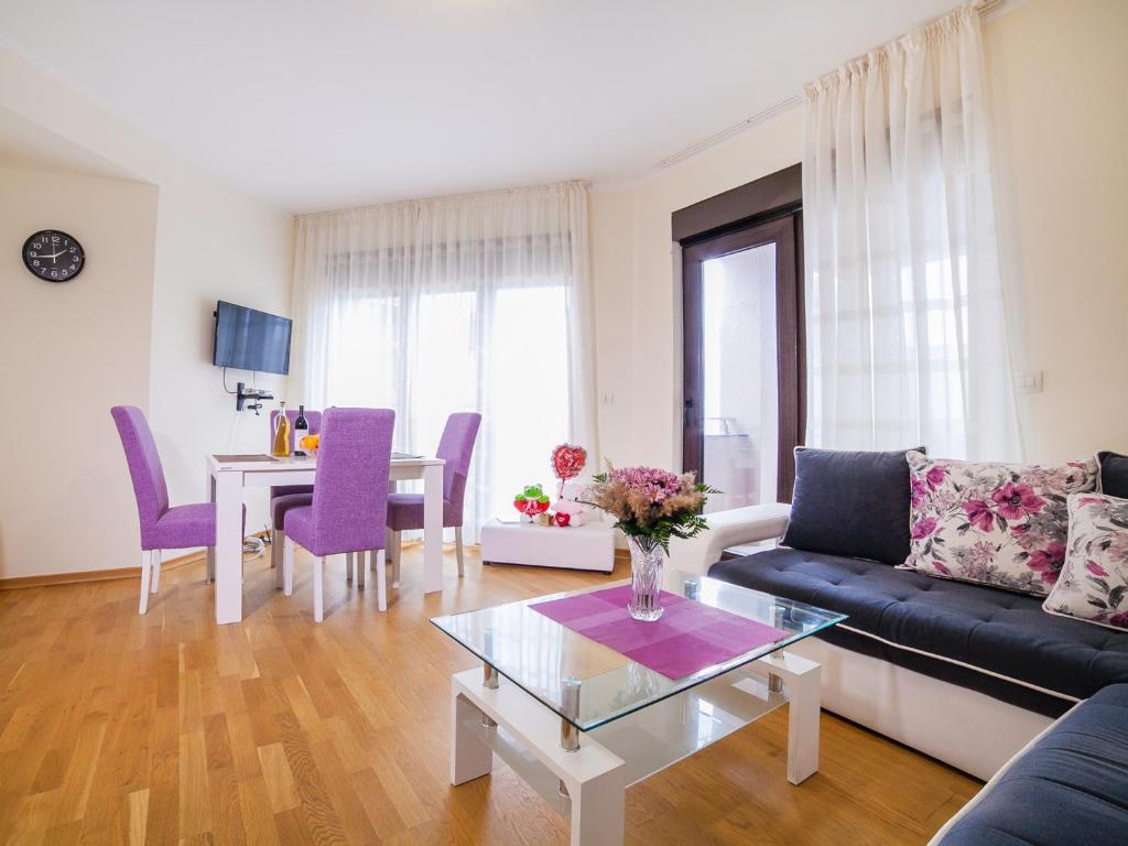 Bel&Rus Sea Apartment في بودفا: غرفة معيشة مع أريكة وطاولة مع كراسي أرجوانية