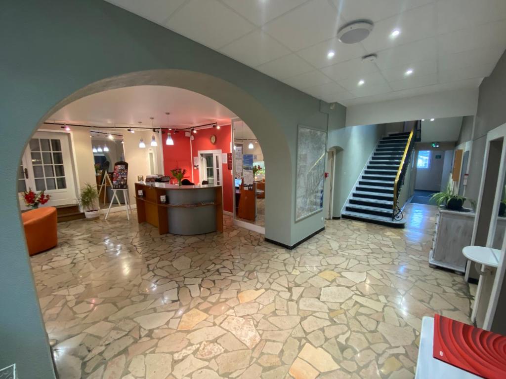 a lobby with an archway and stairs in a building at Nouvel Hotel in Lons-le-Saunier