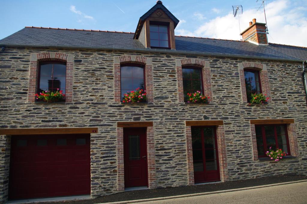 Gîte Des Hirondelles في Pipriac: منزل حجري بأبواب ونوافذ حمراء