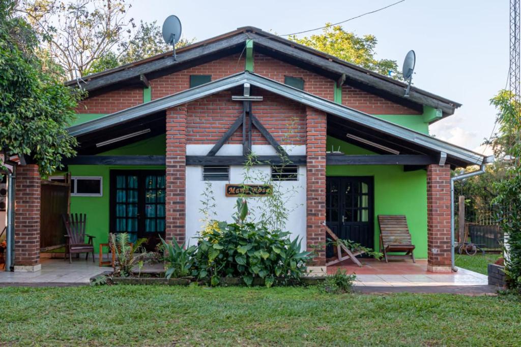 a green and red brick house with a white garage at Cabañas Mama Rosa in Puerto Iguazú