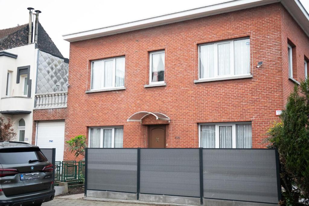 a brick house with a fence in front of it at Cozy family home near LottoArena Antwerpen in Antwerp