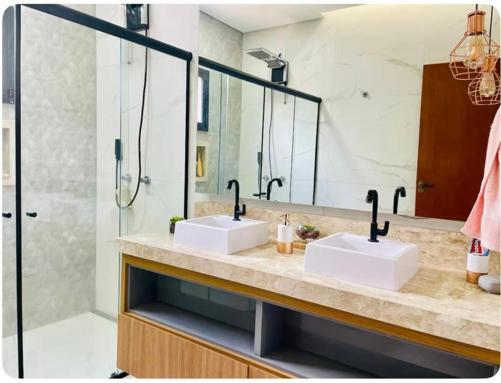 ein Badezimmer mit zwei Waschbecken und einer Dusche in der Unterkunft Casa alto padrão Rio Quente in Rio Quente
