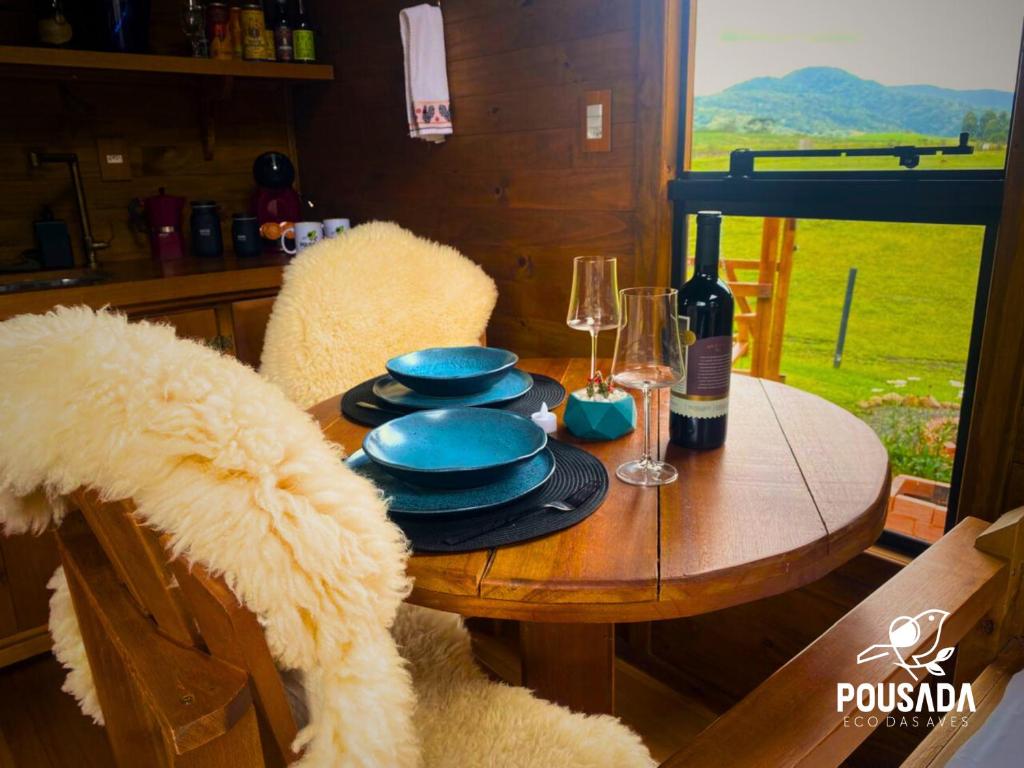 a table with blue plates and wine glasses on it at Chalé na Pousada Eco das Aves próximo a vinícola Thera in Bom Retiro