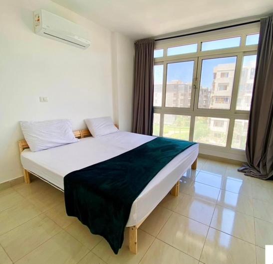 ein Bett in einem Zimmer mit einem großen Fenster in der Unterkunft Hotel in Madinaty