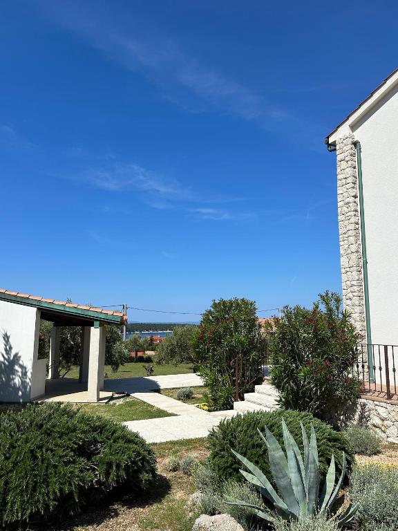 a house with a blue sky and some bushes at Villa Karmen in Barbat na Rabu
