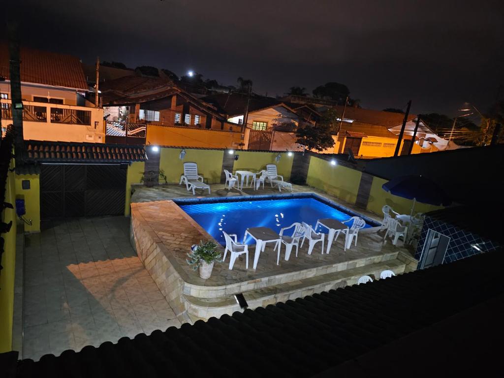 a swimming pool with chairs and a table in front of it at Espetacular casa de temporada na praia in Peruíbe